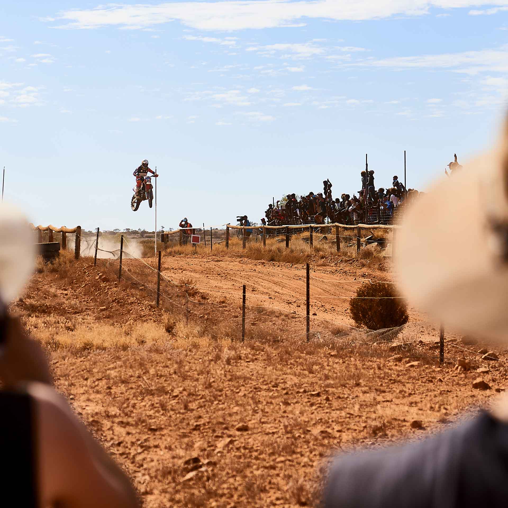 Toby Price jumping the bike in front of Finke spectators
