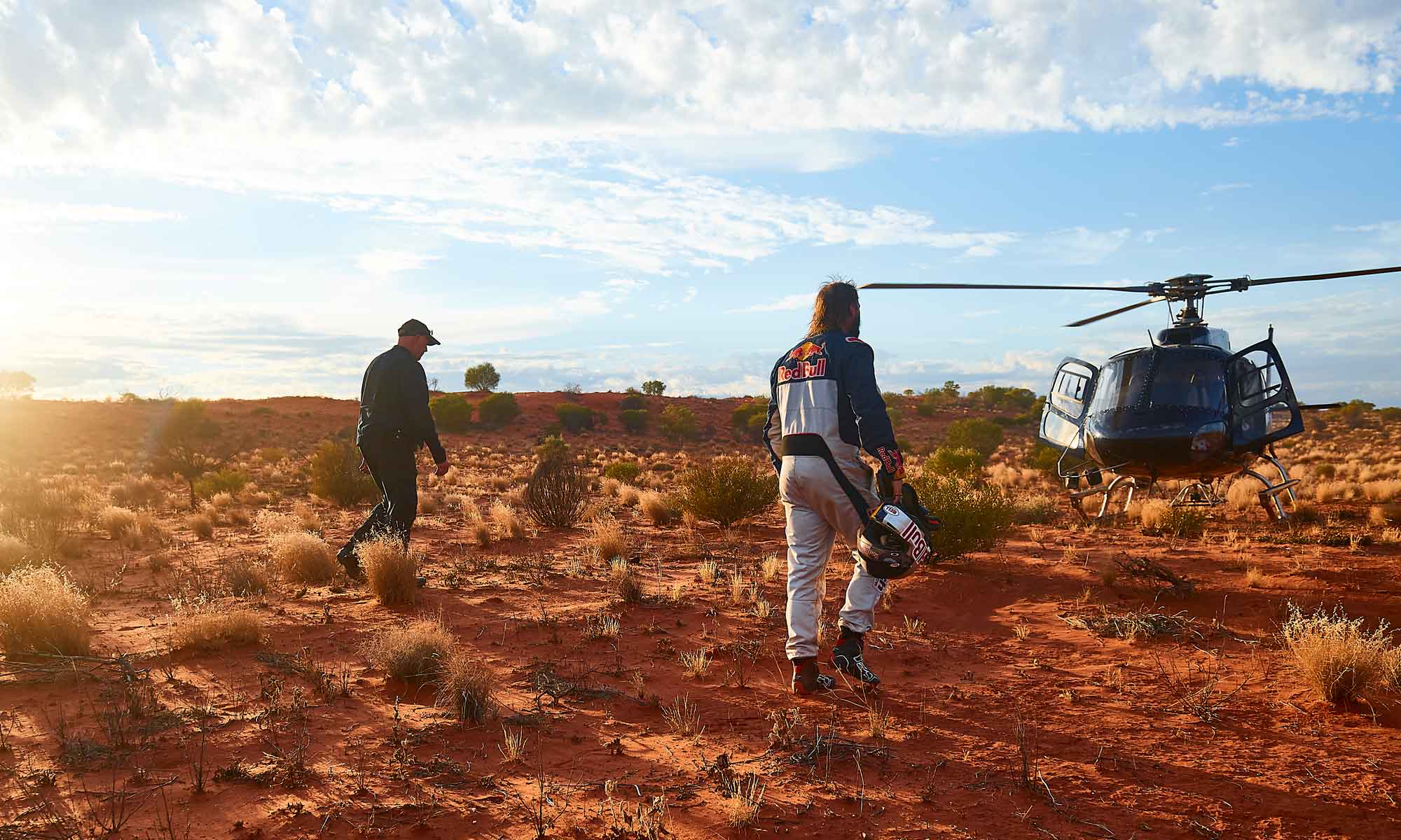Toby Price walking to a waiting helicopter in the desert at sunset
