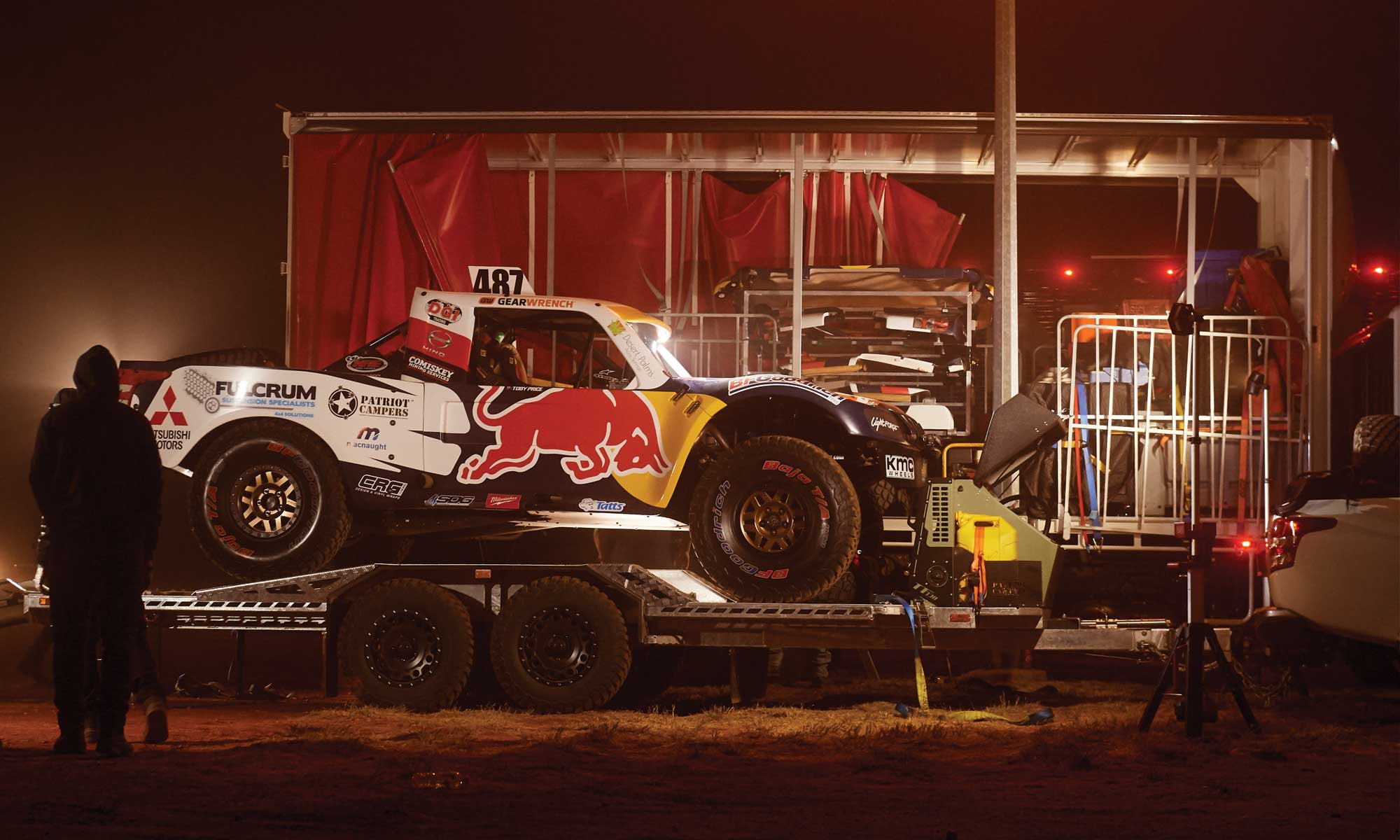 Toby Price's Trophy Truck loaded on a trailer at night