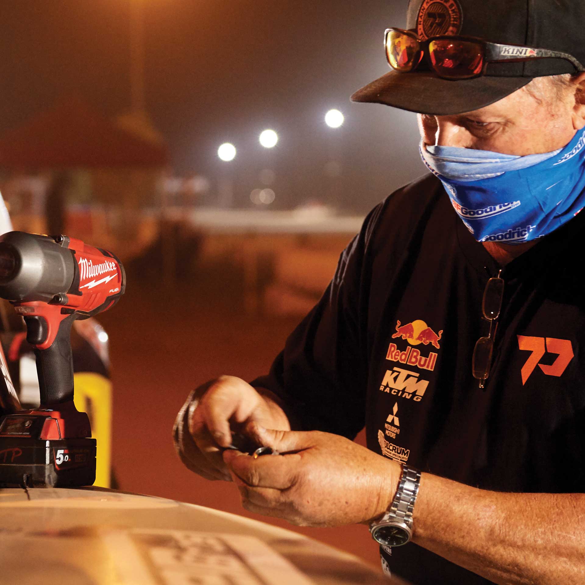 Crew member working on the Trophy Truck under lights