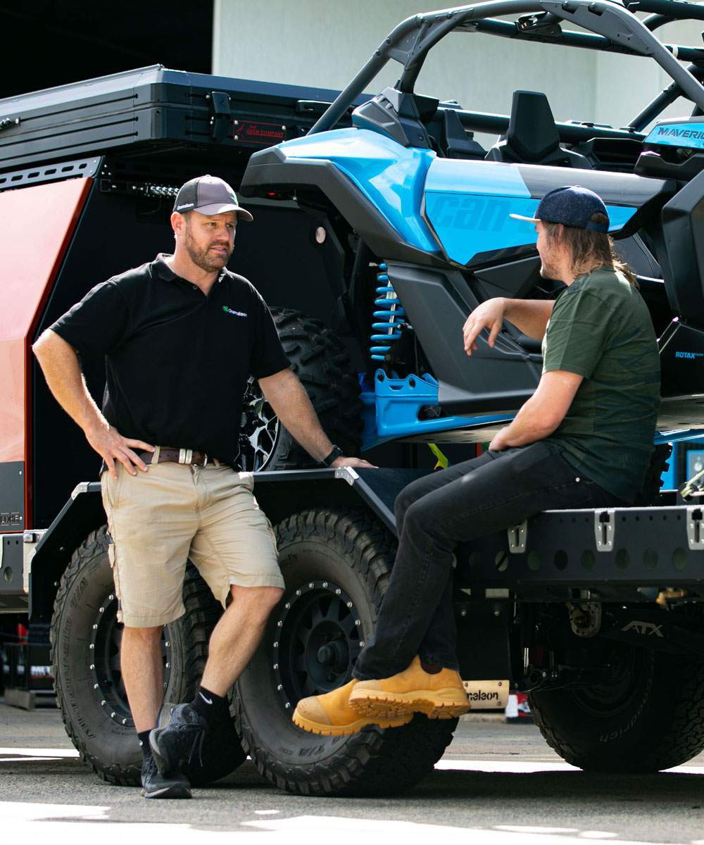 Toby Price with a partner beside a Can-Am Maverick on a trailer
