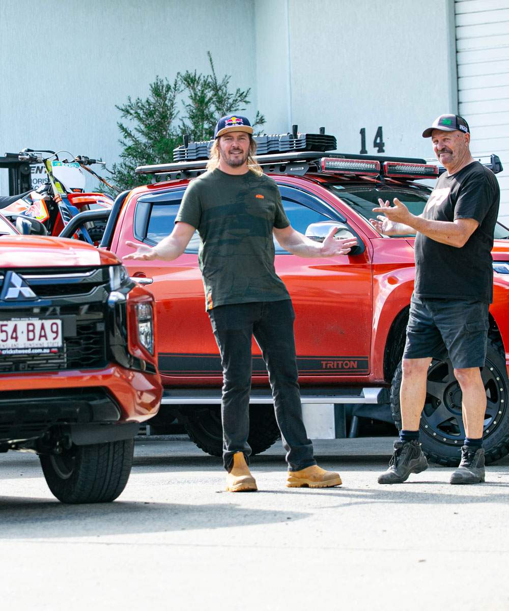 Toby Price with a partner beside a Mitsubishi Triton