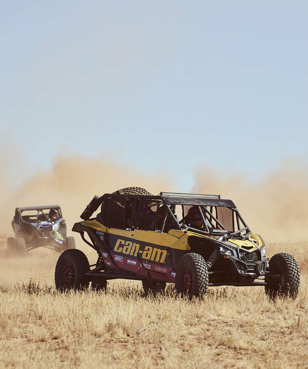 Two Can-Am Maverick X3s kicking up dust across outback grassland