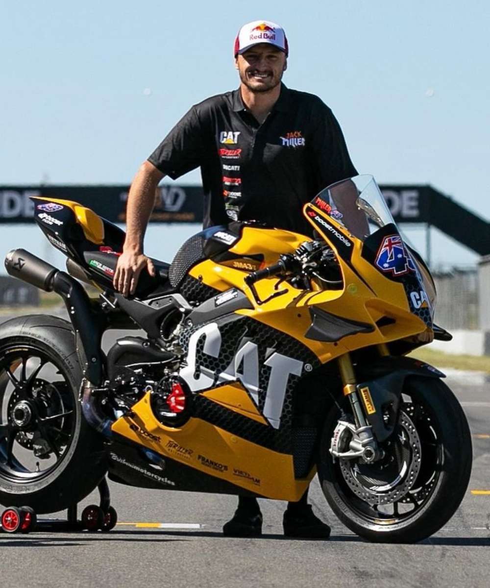 Jack Miller standing beside his Cat-liveried superbike on pit lane