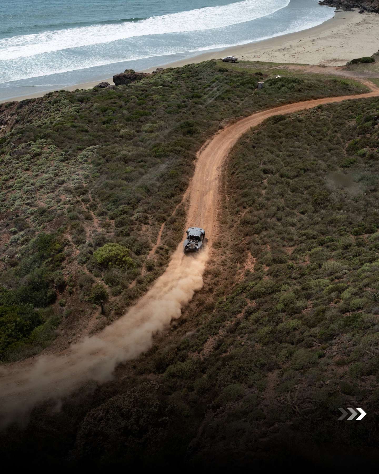 Aerial view of a race vehicle on a coastal Baja dirt road