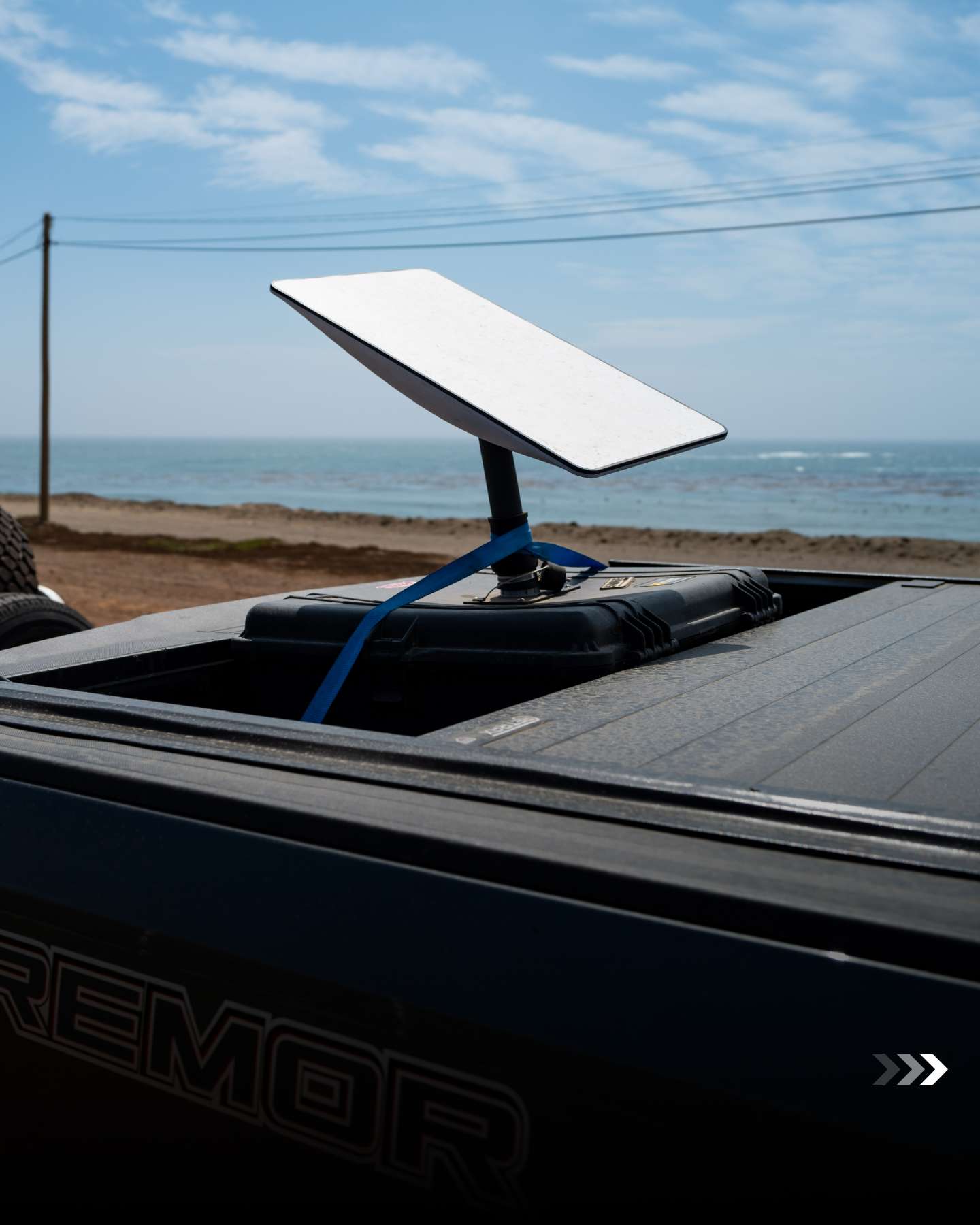 Satellite dish mounted on a support vehicle by the coast