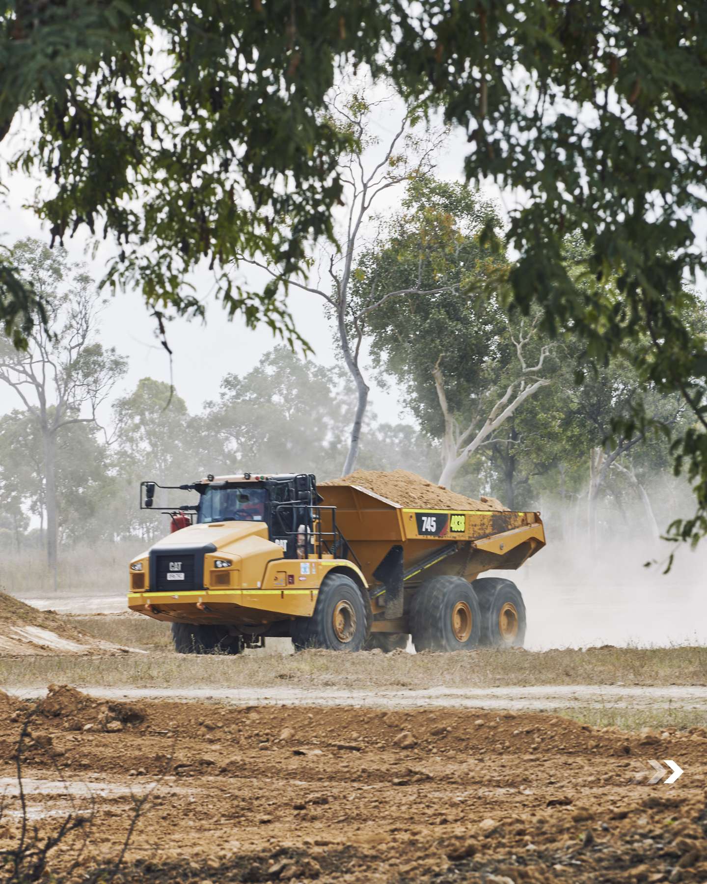 Cat articulated dump truck hauling dirt across the property